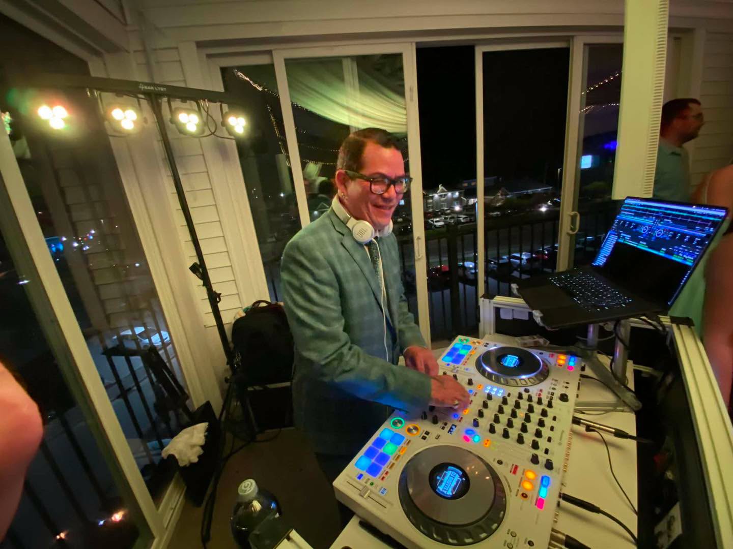DJ Brettly smiling behind his white DJ controller at a wedding reception