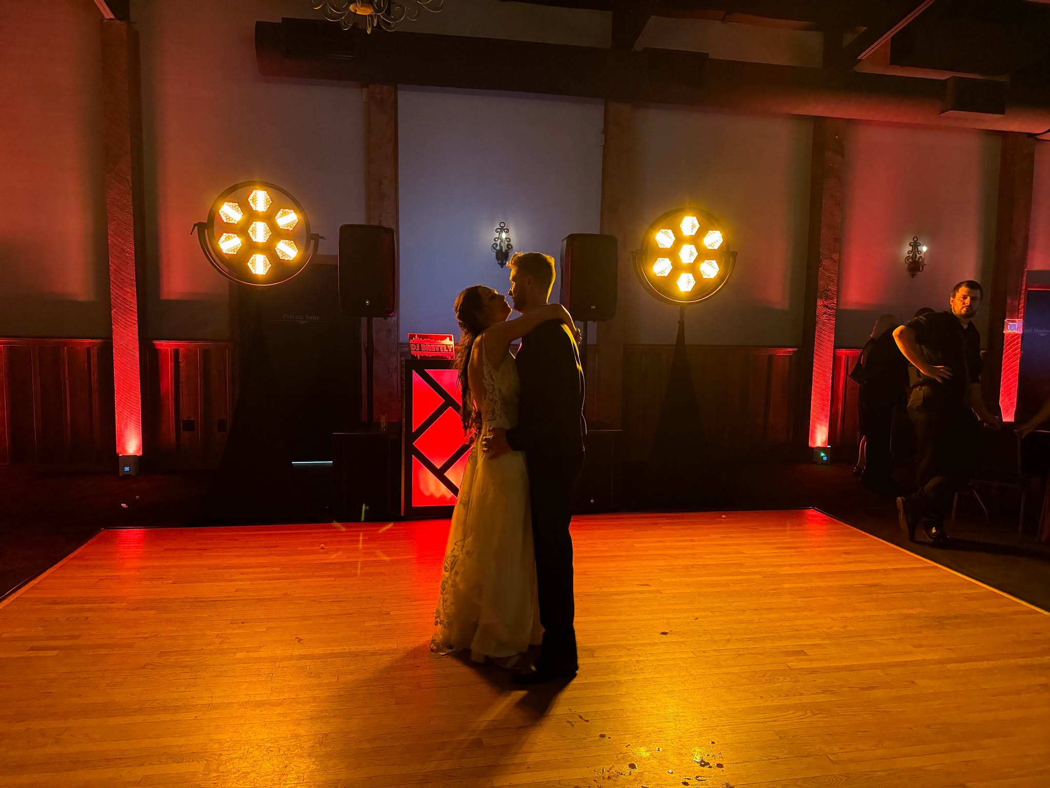 A couple sharing their first dance under warm amber lighting