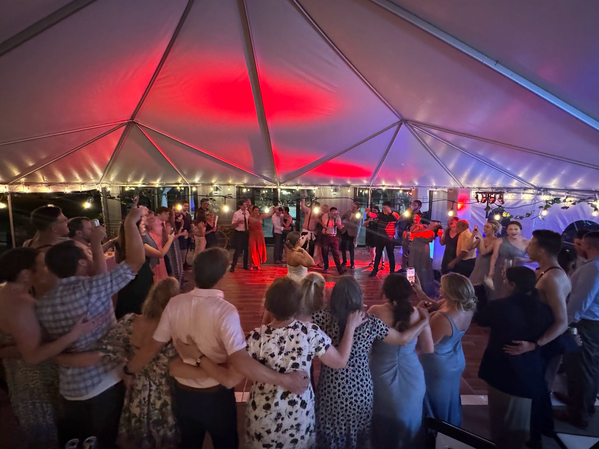 Wedding guests celebrating under a marquee lit in red and blue